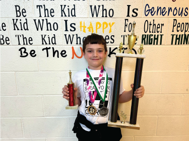 student holding trophy's and medals in hand